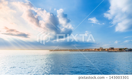 Scenic view over calm blue sea with dramatic cloudy sky and sunbeams Scenic view over calm blue sea with dramatic cloudy sky and sunbeams 143003301