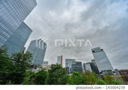 A cloudy day in Umeda, Osaka, with a vast sky stretching above the lush greenery and modern skyscrapers. [Osaka Landscape Photo] 143004239