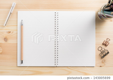 Top view of open lined spiral notebook mockup on light wooden desk 143005699