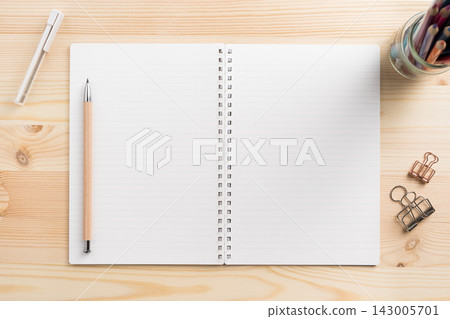 Top view of open lined spiral notebook mockup on light wooden desk 143005701