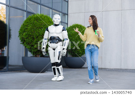 Young woman holding coffee cup and gesturing to robot 143005740
