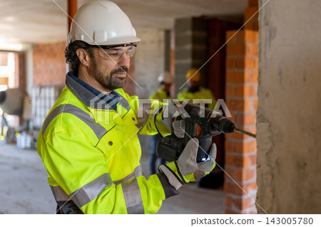 Confident builder operating hammer drill Confident builder operating hammer drill 143005780