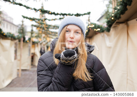 Happy young woman looking at camera at outdoor Christmas market Happy young woman looking at camera at outdoor Christmas market 143005868