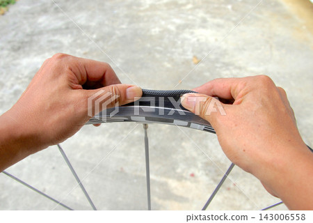 The process of fitting the tire onto the rim with both hands. 143006558