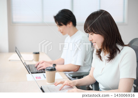 穿著商務休閒服的男男女女正在使用電腦。 143006916
