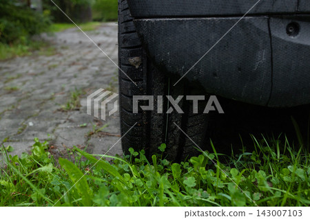 Close-up of a modern car wheel with grey alloy rim on grass 143007103