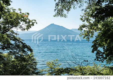 初夏時節,透過樹木眺望北海道支笏湖和福布希山,碧波蕩漾。 初夏時節,透過樹木眺望北海道支笏湖和福布希山,碧波蕩漾。 143007162