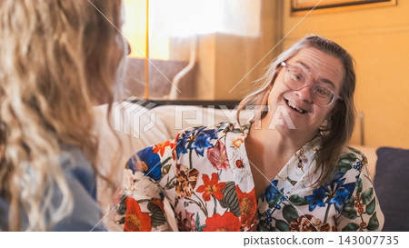 Happy woman with down syndrome smiling and talking to her therapist Happy woman with down syndrome smiling and talking to her therapist 143007735
