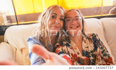 Two smiling women taking selfie on couch: Two smiling women taking selfie on couch: 143007737