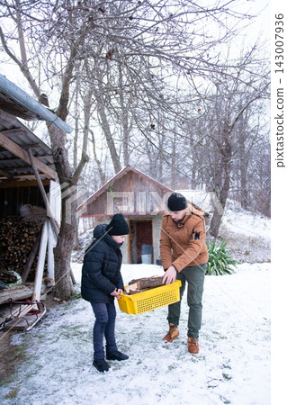 Father and son gather firewood in the snow, a heartwarming winter scene of family teamwork and preparation for the cold. Father and son gather firewood in the snow, a heartwarming winter scene of family teamwork and preparation for the cold. 143007936