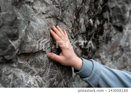 A hand gently touching a beautifully textured rock surface while in a natural setting outdoors A hand gently touching a beautifully textured rock surface while in a natural setting outdoors 143008188