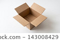 An empty open delivery box made of brown corrugated cardboard sitting on a white table viewed at a 45-degree angle. 143008429