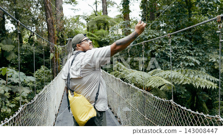 Man hiking Arenal Volcano bridge taking selfie Man hiking Arenal Volcano bridge taking selfie 143008447