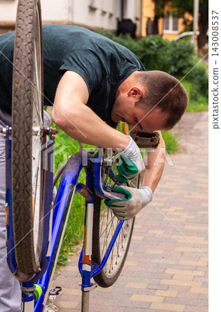 Young man repairing bike chain on sidewalk. Quick fix before summer rides. Responsible transport care and preparation for summer season 143008537