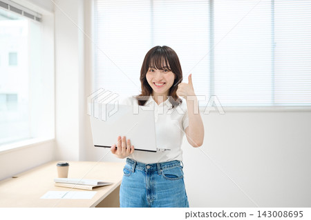 Young women in office casual attire carrying laptops Young women in office casual attire carrying laptops 143008695