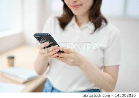 一位身著休閒職業裝的年輕女子手持智慧型手機 143008810