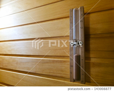 Wooden hourglass hanging on light wooden sauna wall Wooden hourglass hanging on light wooden sauna wall 143008877