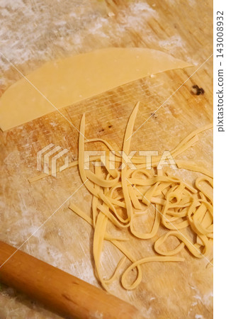 Fresh raw egg noodles and rolling pin on wooden board Fresh raw egg noodles and rolling pin on wooden board 143008932