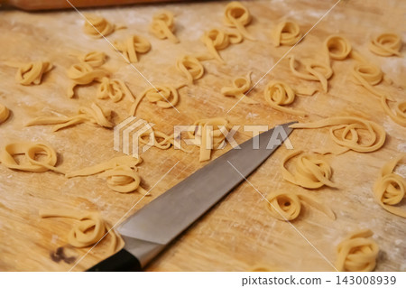 Top view of homemade noodles and knife on wooden board Top view of homemade noodles and knife on wooden board 143008939