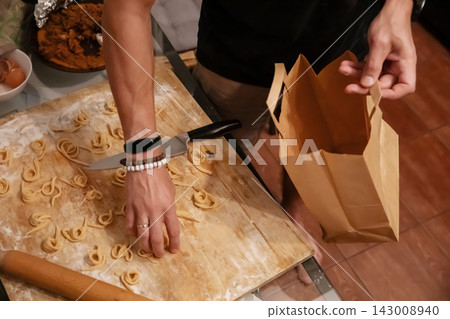 Hands putting fresh homemade noodles into paper bag Hands putting fresh homemade noodles into paper bag 143008940