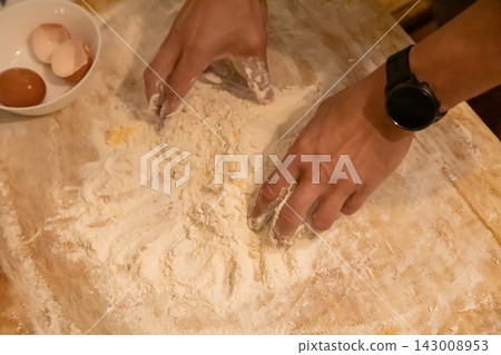 Hands mixing flour and egg for homemade pasta dough Hands mixing flour and egg for homemade pasta dough 143008953