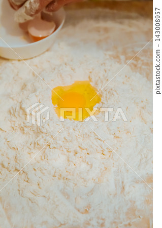 Raw egg yolk in flour well for making pasta dough Raw egg yolk in flour well for making pasta dough 143008957