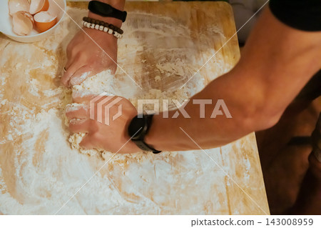 Hands kneading flour and egg into homemade pasta dough Hands kneading flour and egg into homemade pasta dough 143008959