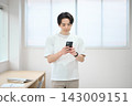 一位身著休閒職業裝的年輕男子手持智慧型手機 143009151