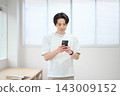 一位身著休閒職業裝的年輕男子手持智慧型手機 143009152