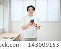 一位身著休閒職業裝的年輕男子手持智慧型手機 143009153
