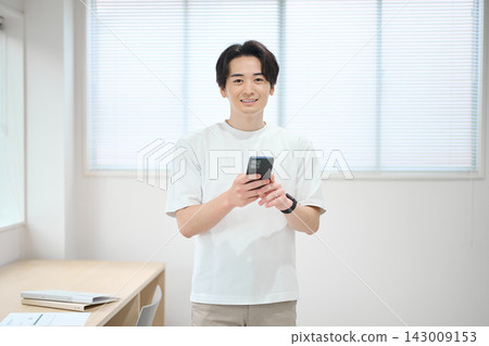 一位身著休閒職業裝的年輕男子手持智慧型手機 一位身著休閒職業裝的年輕男子手持智慧型手機 143009153