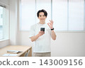 一位身著休閒職業裝的年輕男子手持智慧型手機 143009156