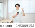 一位身著休閒職業裝的年輕男子手持智慧型手機 143009158