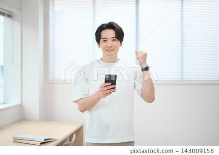 一位身著休閒職業裝的年輕男子手持智慧型手機 143009158