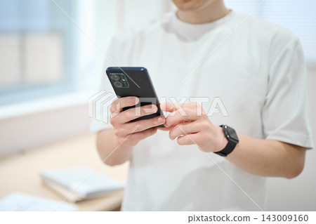一位身著休閒職業裝的年輕男子手持智慧型手機 一位身著休閒職業裝的年輕男子手持智慧型手機 143009160