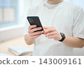 一位身著休閒職業裝的年輕男子手持智慧型手機 143009161