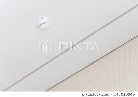 Smoke detector on white ceiling in room corner Smoke detector on white ceiling in room corner 143010049