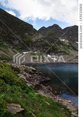 Mountain lake with rocky shore and steep cliffs Mountain lake with rocky shore and steep cliffs 143010068