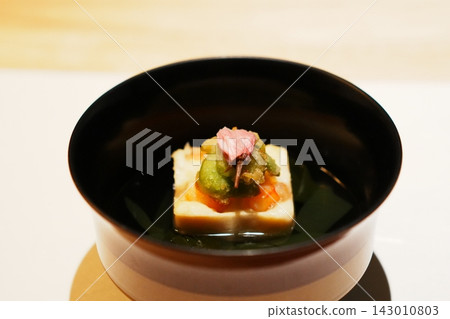 A soup dish with tofu and cherry blossoms floating in a lacquered bowl. A soup dish with tofu and cherry blossoms floating in a lacquered bowl. 143010803