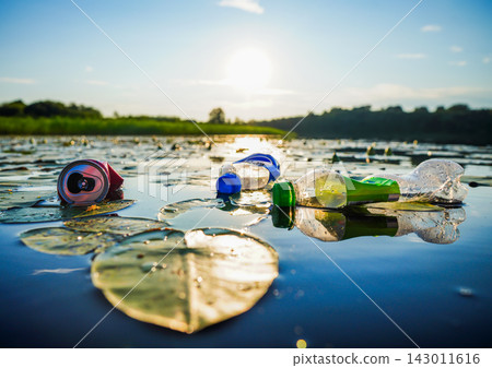 Plastic bottle discarded in river floats among aquatic vegetation and water lilies. Plastic bottle discarded in river floats among aquatic vegetation and water lilies. 143011616