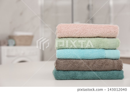 Stack of color towels on white table in bathroom Stack of color towels on white table in bathroom 143012040