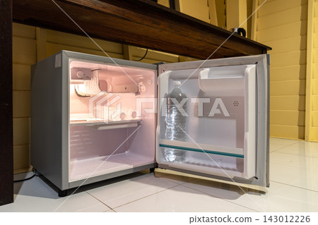 Mini refrigerator, wooden cabinet, and open wardrobe create a simple room layout focused on storage, practical furniture, and everyday accommodation use. Mini refrigerator, wooden cabinet, and open wardrobe create a simple room layout focused on storage, practical furniture, and everyday accommodation use. 143012226