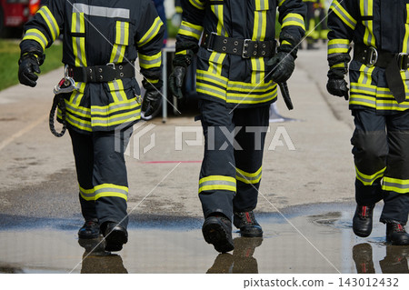 Firefighters Walking in Reflective Protective Gear and Boots During Emergency Response Training Exercise Firefighters Walking in Reflective Protective Gear and Boots During Emergency Response Training Exercise 143012432