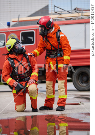 Firefighters in Protective Gear Providing Support Next To Red Fire Truck During Emergency Training Firefighters in Protective Gear Providing Support Next To Red Fire Truck During Emergency Training 143012457