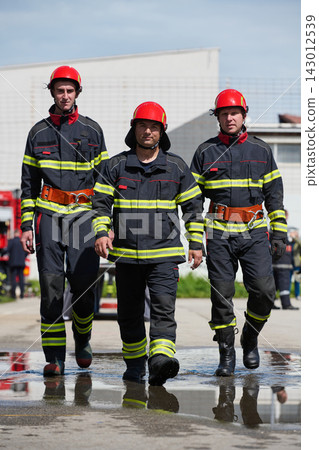 Firefighters Team Walking Together in Protective Gear With Red Helmets During Emergency Response Training 143012539