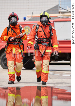 Two Firefighters in Full Protective Gear Walking in Front of Fire Truck During Emergency Response Two Firefighters in Full Protective Gear Walking in Front of Fire Truck During Emergency Response 143012696