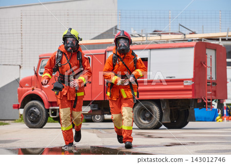Firefighters In Full Protective Gear Running From Red Fire Truck During Emergency Response Drill Firefighters In Full Protective Gear Running From Red Fire Truck During Emergency Response Drill 143012746