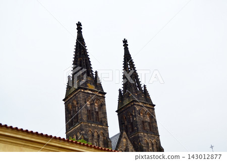 Twin gothic spires rising above rooftops at vysehrad in prague for architectural background and heritage banner use Twin gothic spires rising above rooftops at vysehrad in prague for architectural background and heritage banner use 143012877