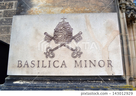 Basilica of St Peter and St Paul, Prague. Stone plaque reading basilica minor with papal emblem and crossed keys on historic church exterior for heritage signage 143012929