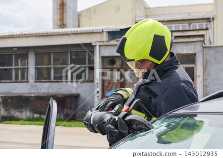 Firefighter Performing Vehicle Rescue Extrication With Hydraulic Tool At Car Accident Scene During Training Firefighter Performing Vehicle Rescue Extrication With Hydraulic Tool At Car Accident Scene During Training 143012935